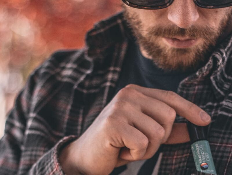 A person holds a bottle of CBD oil, highlighting its non-psychoactive properties and potential therapeutic uses according to the article.