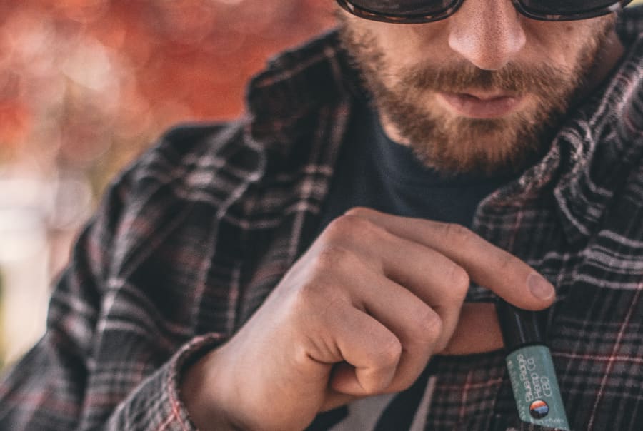 A person holds a bottle of CBD oil, highlighting its non-psychoactive properties and potential therapeutic uses according to the article.