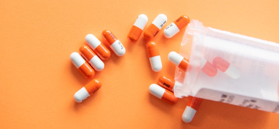 A cascade of prescription pills spilling out from an open bottle, symbolizing the prevalence of prescription drug misuse.