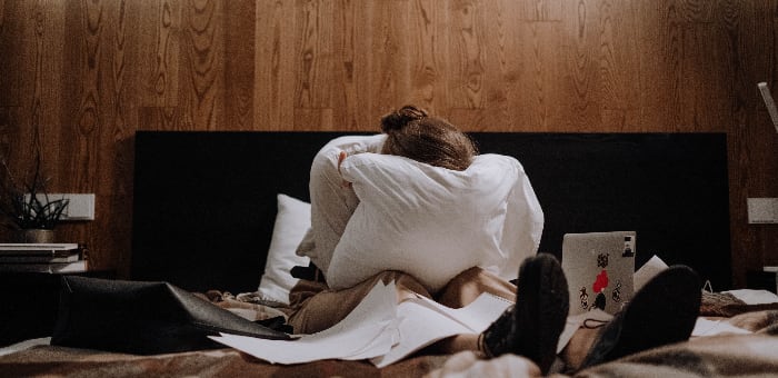 A distressed woman lies on a couch, her face contorted with the visible pain of withdrawal symptoms.