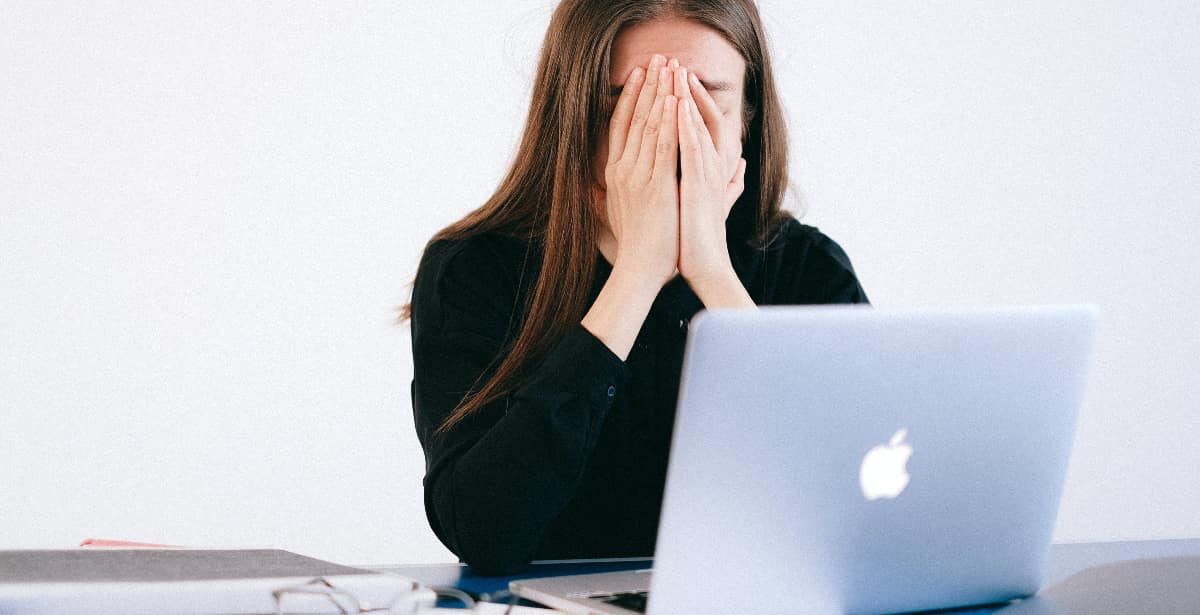 A woman with her hands covering her face, depicting distress and despair, symbolizing job loss due to the characteristics of alcoholism.