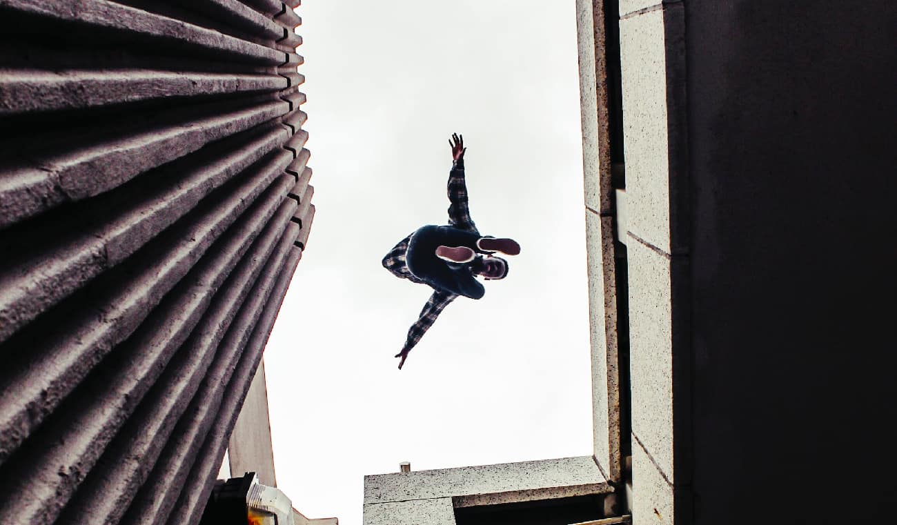 Person perilously jumping between two skyscrapers, illustrating the extreme risks and potential consequences associated with the dangerous practice of freebasing.