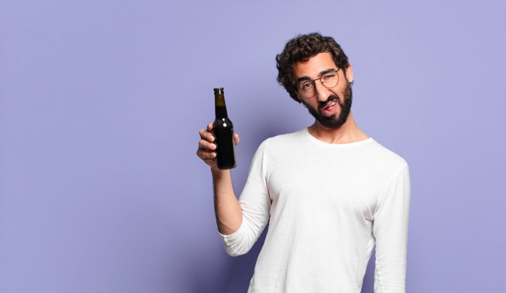 Man holding a beer bottle asking if it is dangerous to detox from alcohol on your own