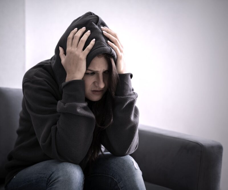 Woman in a hoodie experiencing severe alcohol withdrawal symptoms