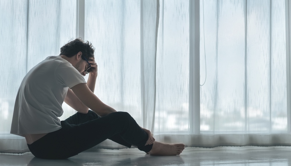 Male sitting on the floor struggling with withdrawal symptoms from cocaine drug use