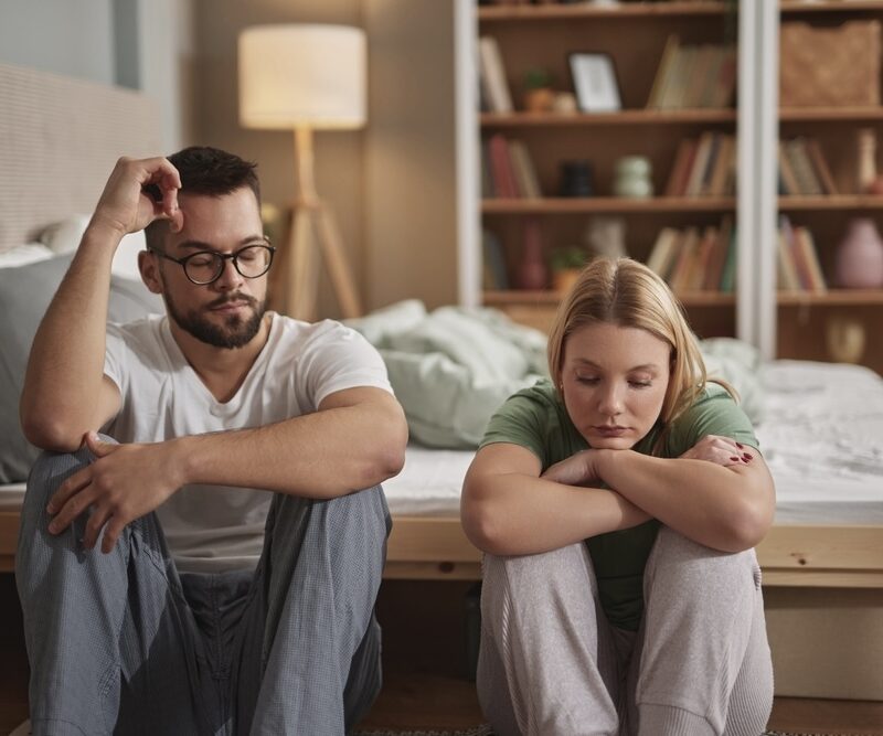 Husband and wife seated on the floor of their bedroom discussing alcohol detox treatment