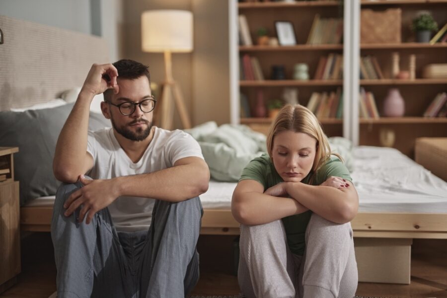 Husband and wife seated on the floor of their bedroom discussing alcohol detox treatment