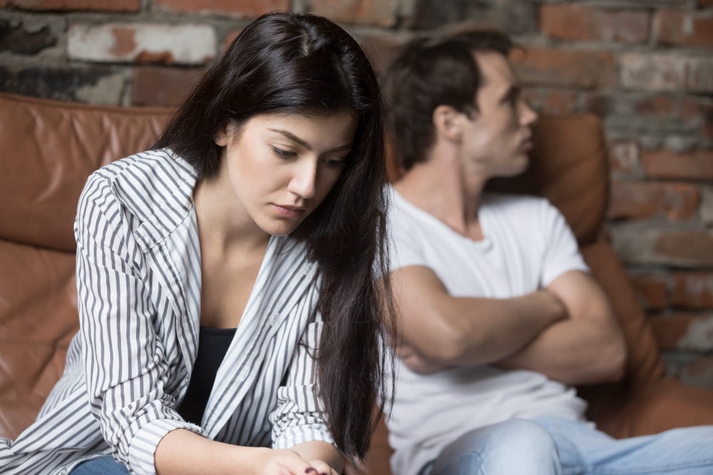 Couple sitting on a couch having a hard time talking about seeking drug detox treatment